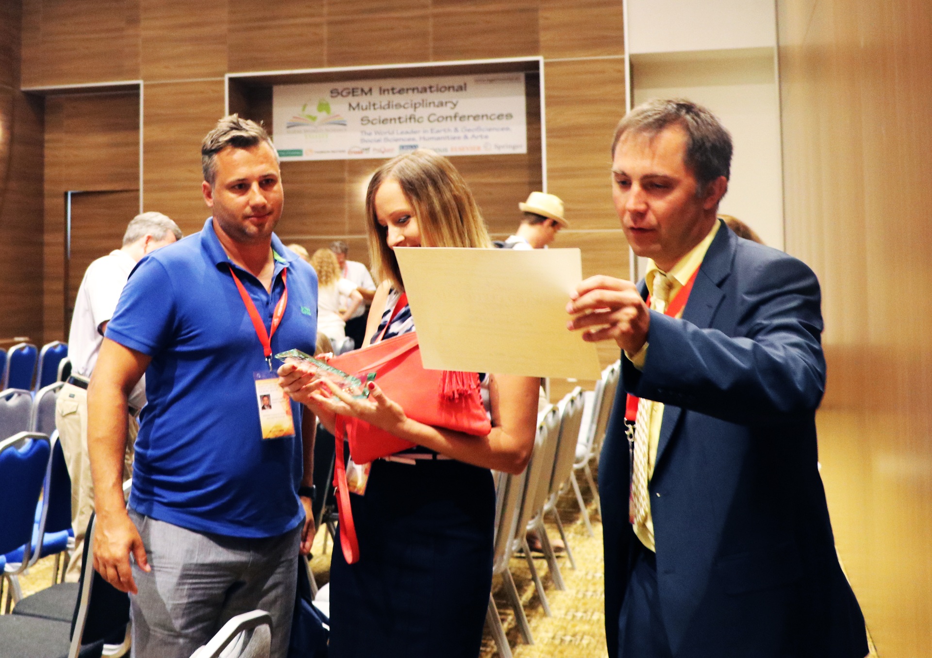 Three conference participants discussing a certificate